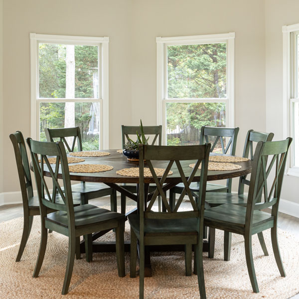 A dining room table with seating for eight in a room full of windows and light.